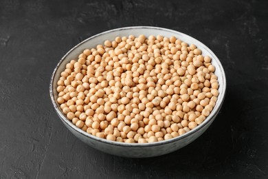 Dried peas in bowl on dark textured table, closeup