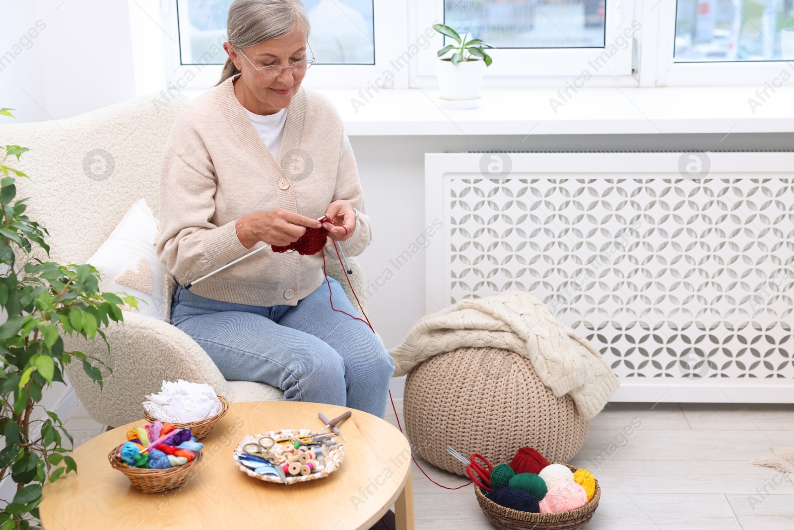 Photo of Beautiful senior woman knitting on armchair at home