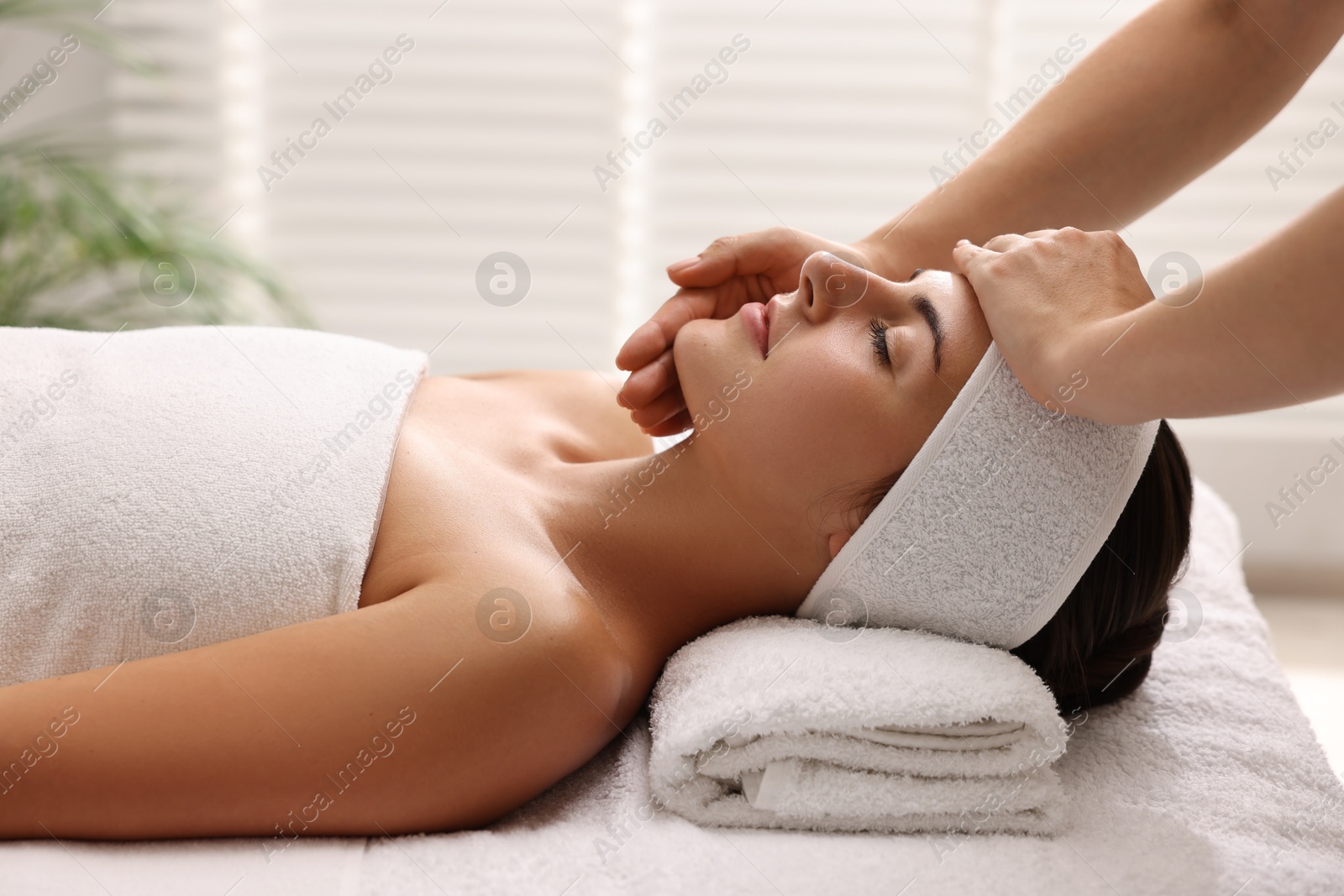 Photo of Attractive woman enjoying face massage in spa salon