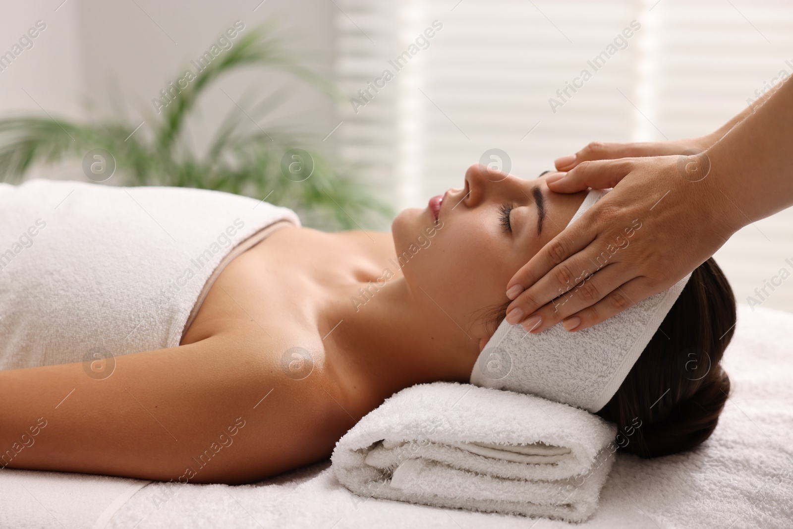 Photo of Attractive woman enjoying face massage in spa salon