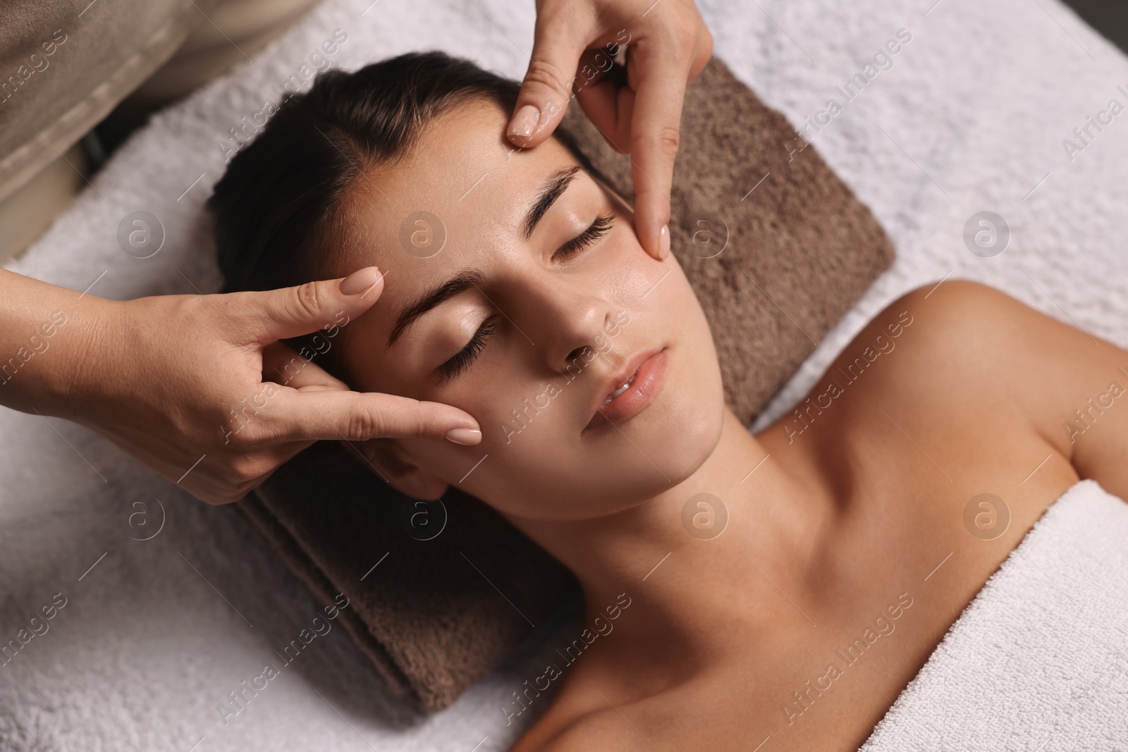 Photo of Attractive woman enjoying face massage, above view. Beauty procedure