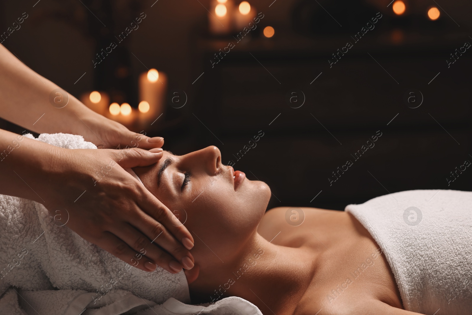 Photo of Attractive woman enjoying face massage in spa salon, closeup