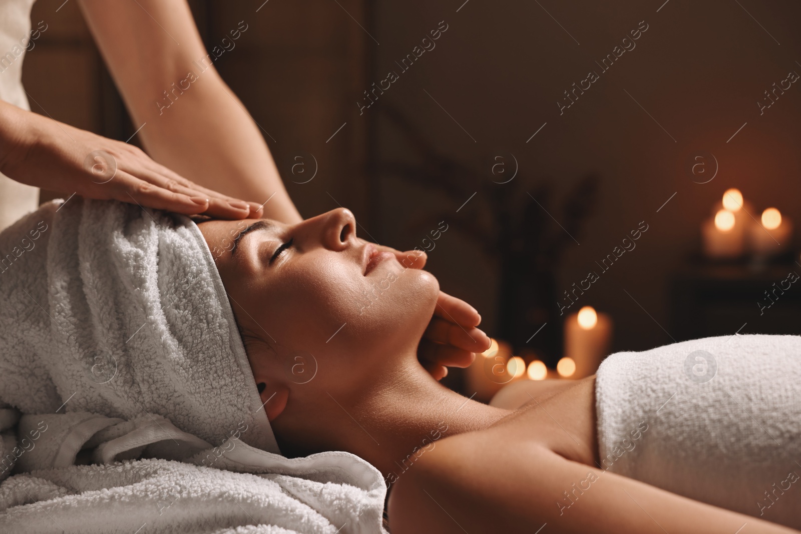 Photo of Attractive woman enjoying face massage in spa salon, closeup