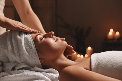 Attractive woman enjoying face massage in spa salon, closeup