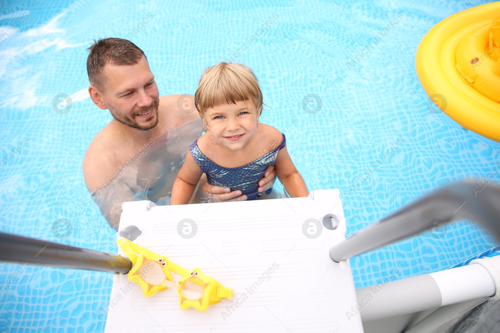 Photo of Happy daughter and her father near ladder in swimming pool, above view