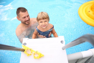 Photo of Happy daughter and her father near ladder in swimming pool, above view