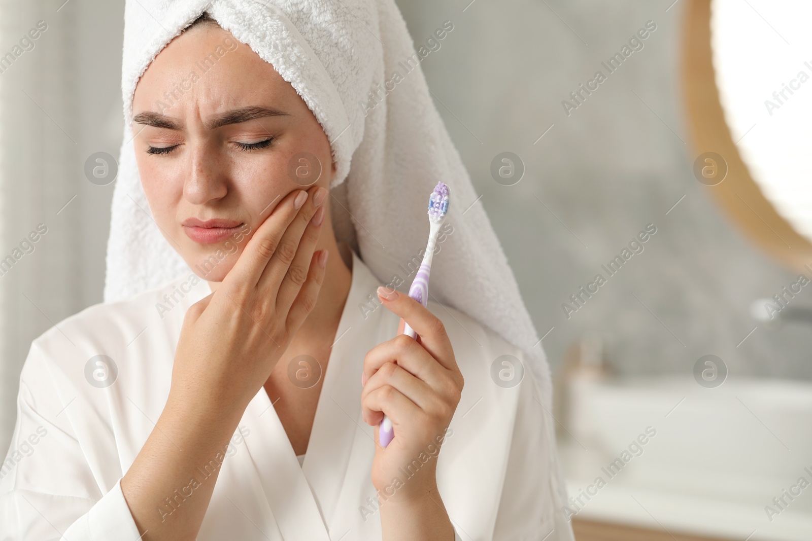 Photo of Young woman with toothbrush suffering from toothache in bathroom