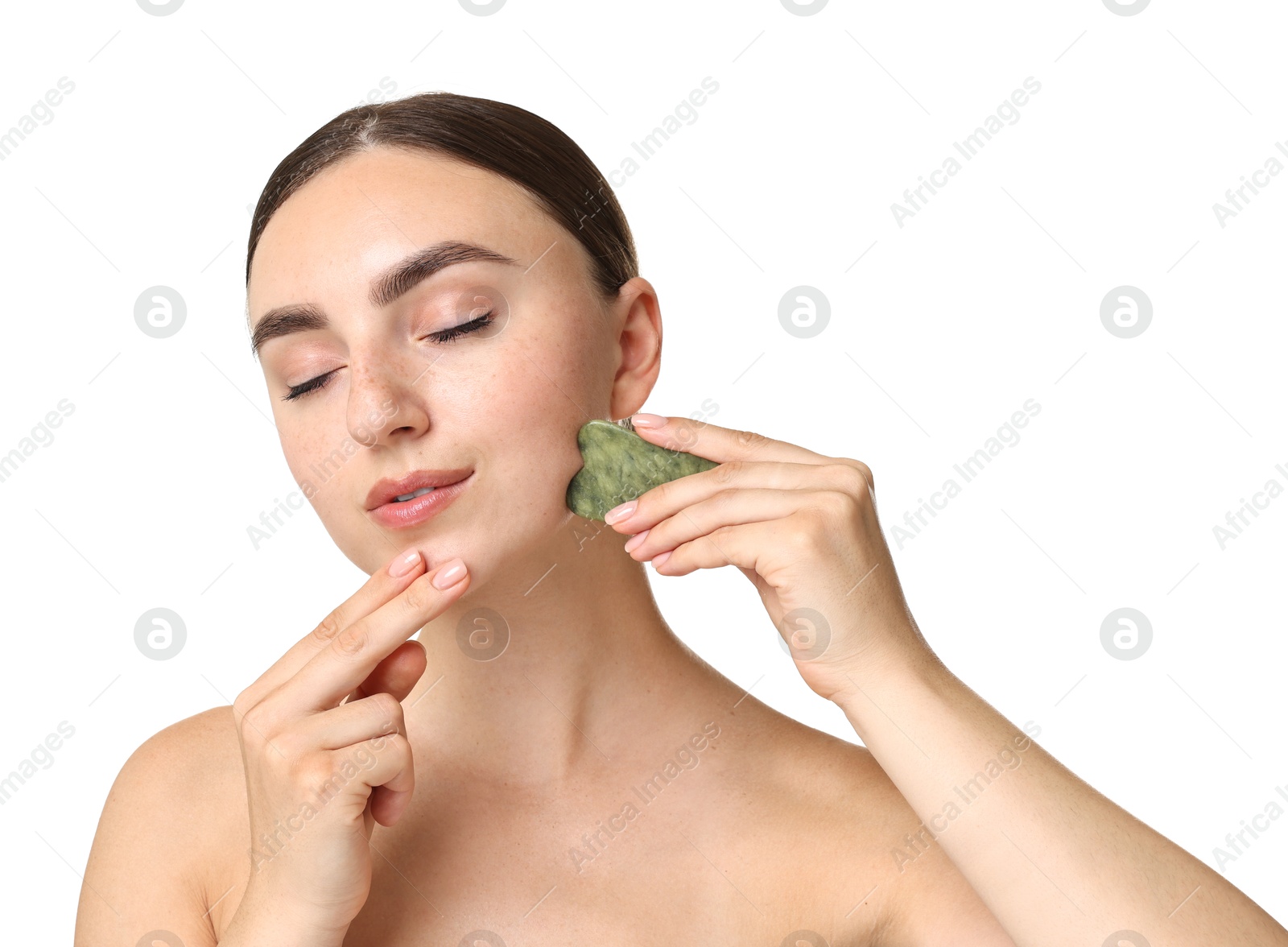 Photo of Beautiful young woman doing facial massage with gua sha tool on white background