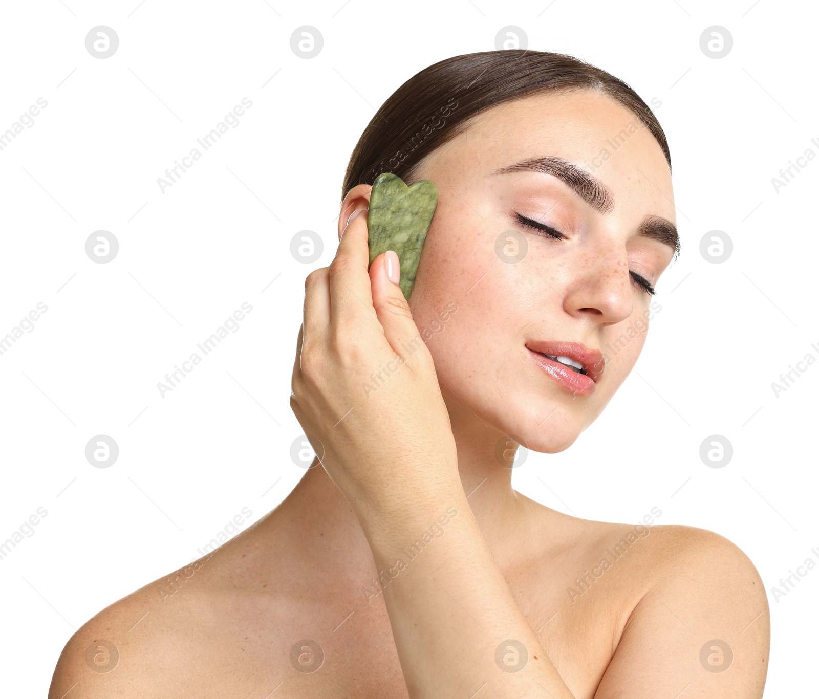 Photo of Beautiful young woman doing facial massage with gua sha tool on white background