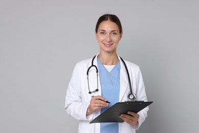 Photo of Nurse in medical uniform with stethoscope and clipboard on grey background