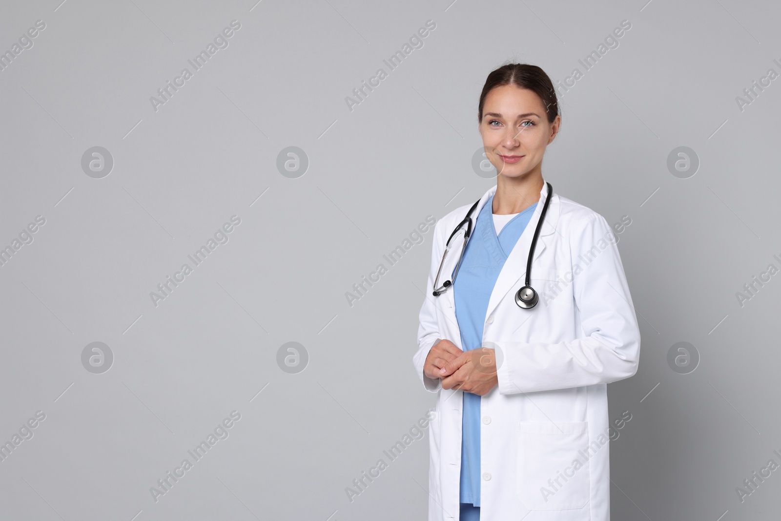 Photo of Nurse in medical uniform with stethoscope on grey background, space for text