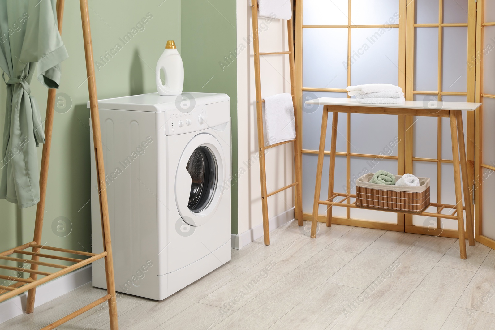 Photo of Washing machine, towels and detergent in laundry room