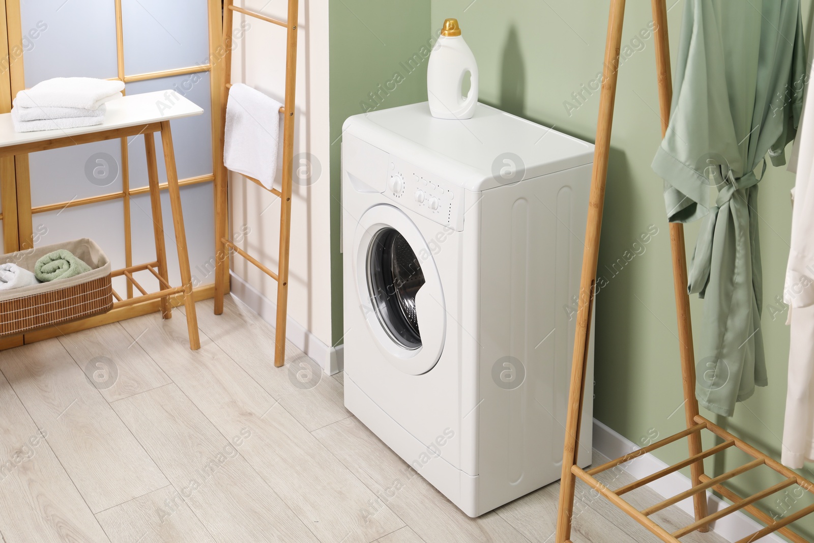 Photo of Washing machine, towels and detergent in laundry room