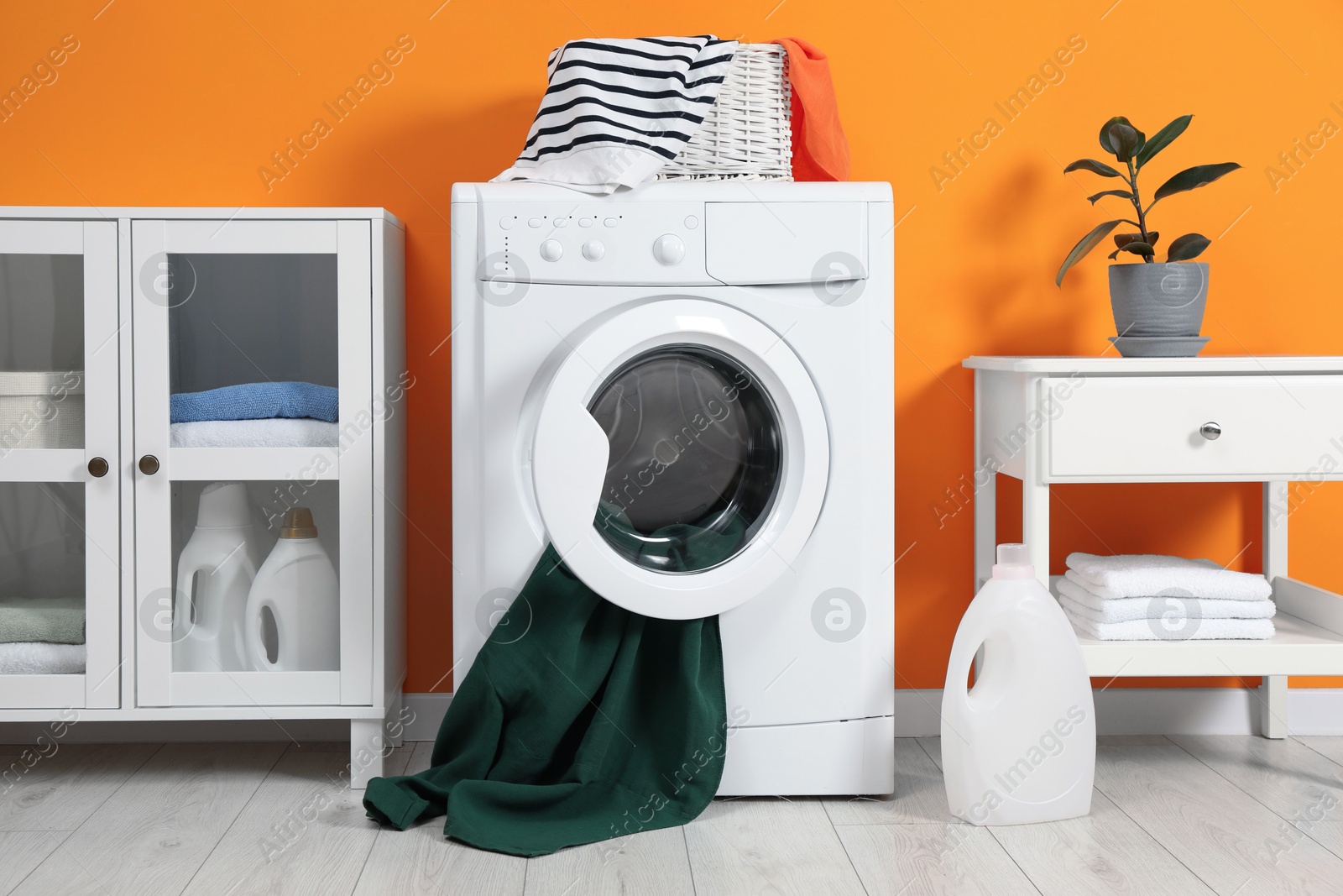 Photo of Washing machine, towels and detergents in laundry room