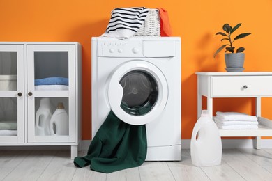 Photo of Washing machine, towels and detergents in laundry room