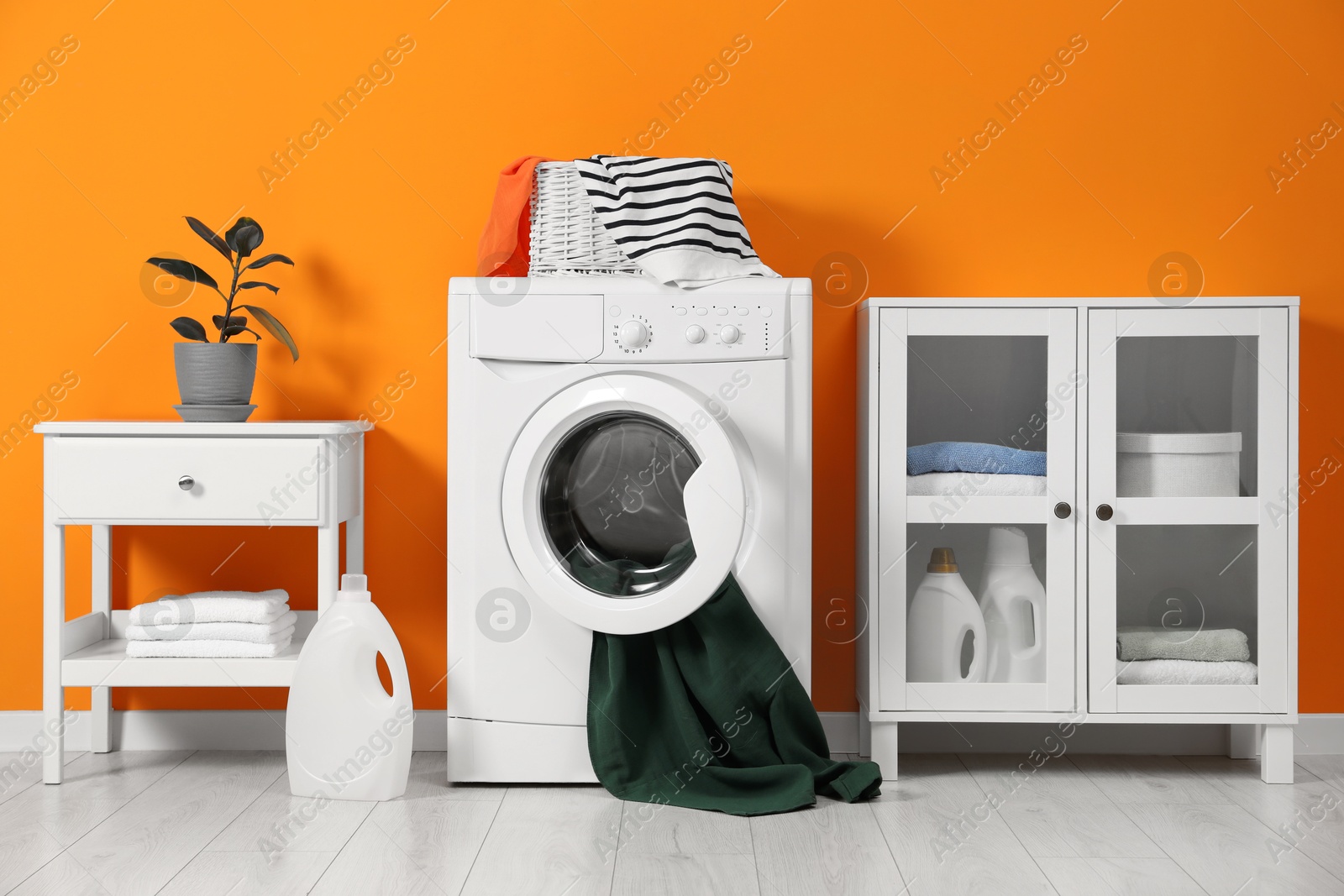 Photo of Washing machine, towels and detergents in laundry room