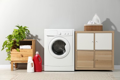 Photo of Washing machine, towels and detergents in laundry room