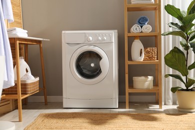 Photo of Washing machine, towels and detergents in laundry room