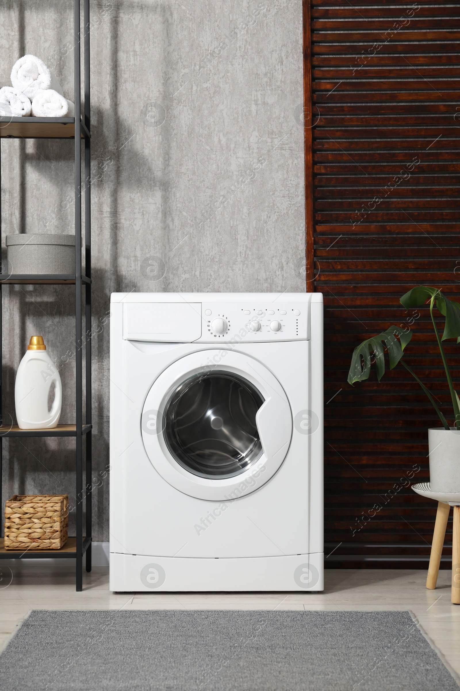 Photo of Washing machine, towels and detergents in laundry room