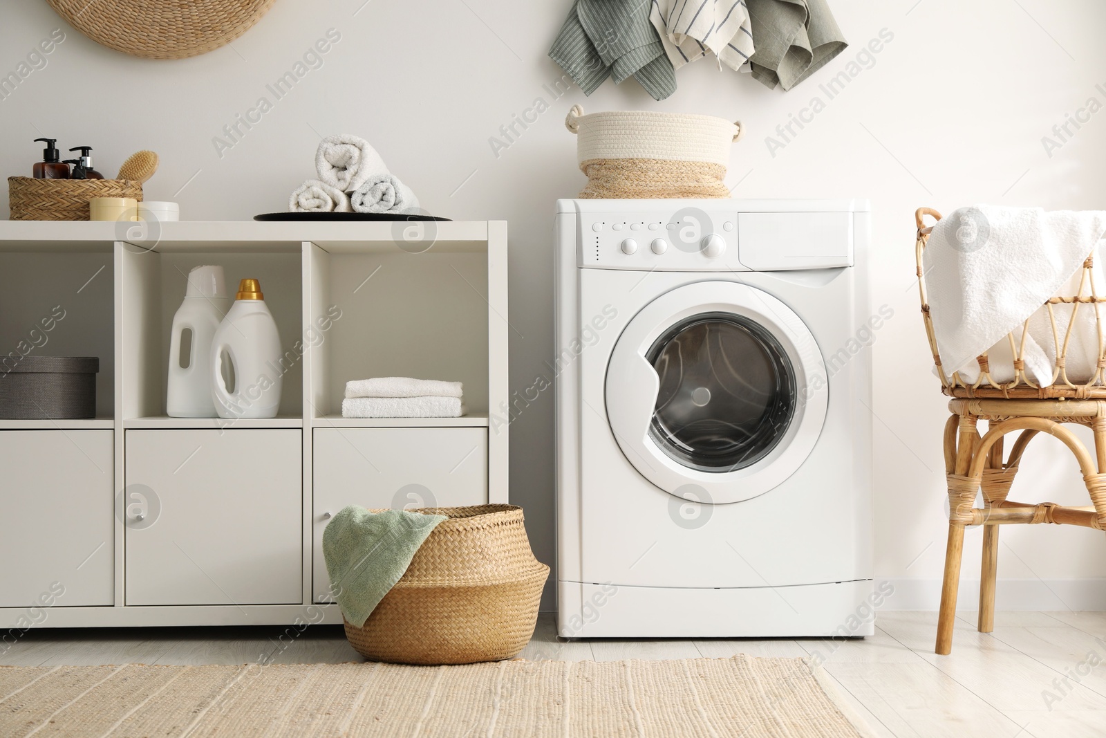 Photo of Washing machine, towels and detergents in laundry room