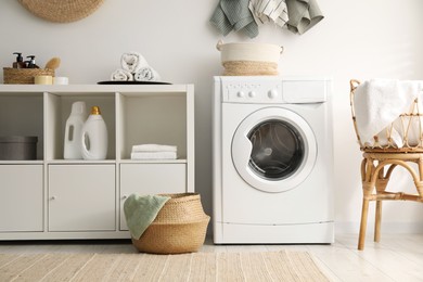 Photo of Washing machine, towels and detergents in laundry room