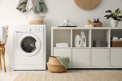 Photo of Washing machine, towels and detergents in laundry room