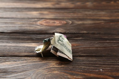 Photo of One crumpled dollar banknote on wooden table, closeup