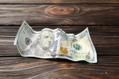 Photo of One crumpled dollar banknote on wooden table, closeup