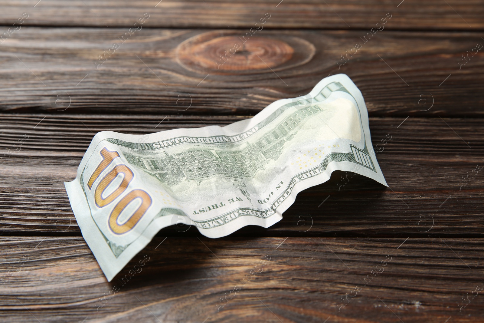 Photo of One crumpled dollar banknote on wooden table, closeup