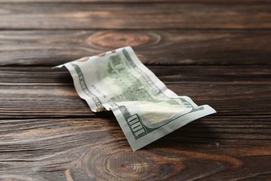 Photo of One crumpled dollar banknote on wooden table, closeup