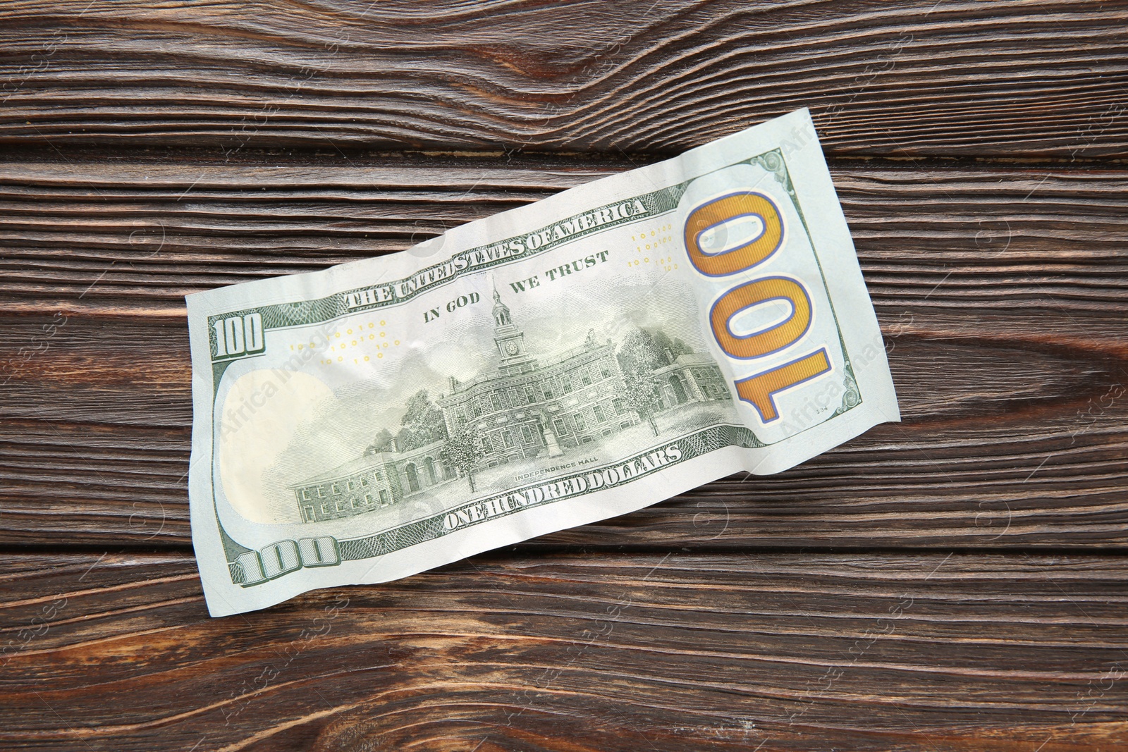 Photo of One crumpled dollar banknote on wooden table, top view