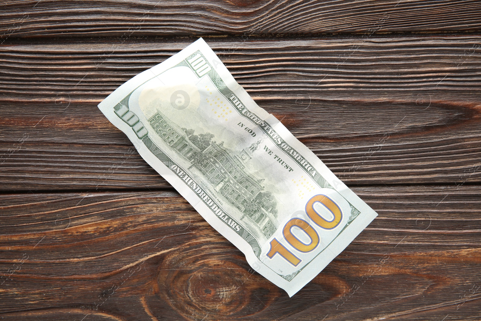 Photo of One crumpled dollar banknote on wooden table, top view