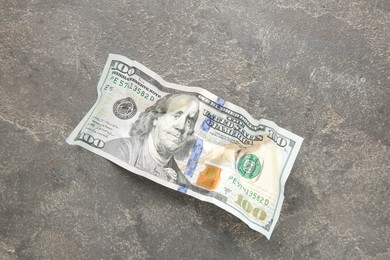 Photo of One crumpled dollar banknote on grey table, top view