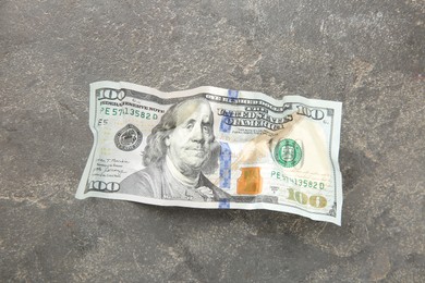 Photo of One crumpled dollar banknote on grey table, top view