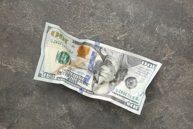 Photo of One crumpled dollar banknote on grey table, top view