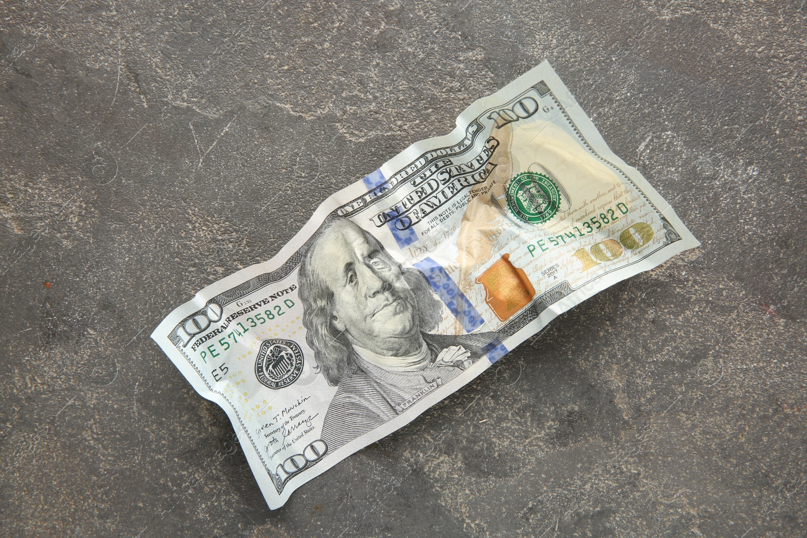 Photo of One crumpled dollar banknote on grey table, top view