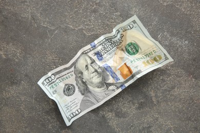 Photo of One crumpled dollar banknote on grey table, top view