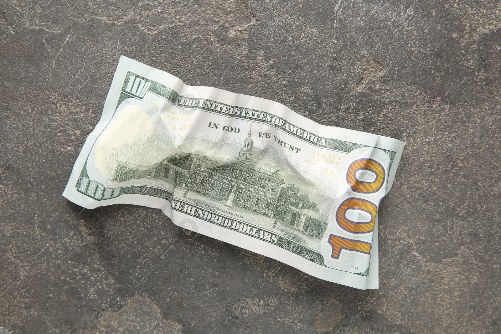 Photo of One crumpled dollar banknote on grey table, top view