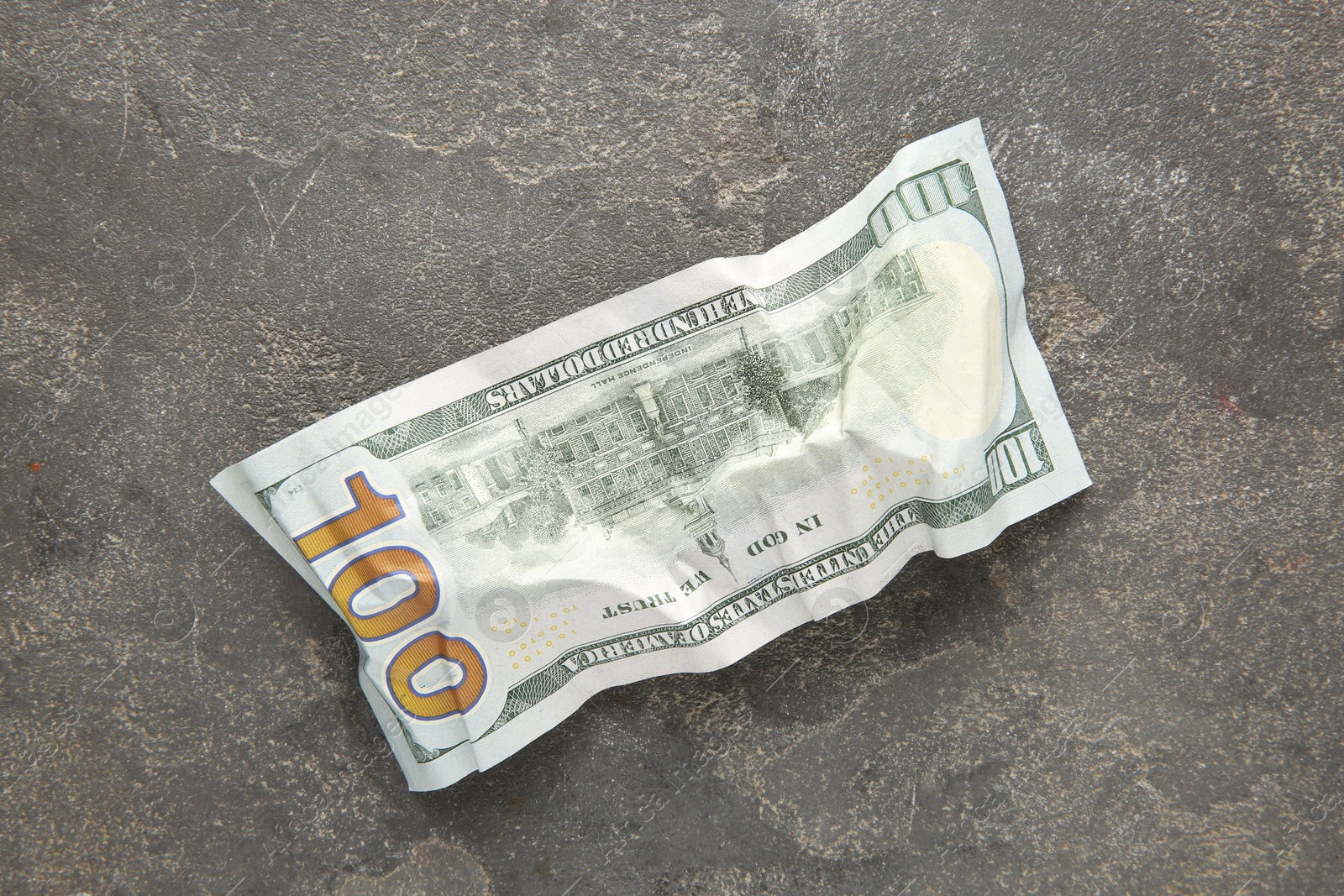 Photo of One crumpled dollar banknote on grey table, top view