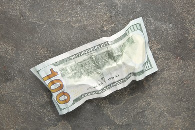 Photo of One crumpled dollar banknote on grey table, top view