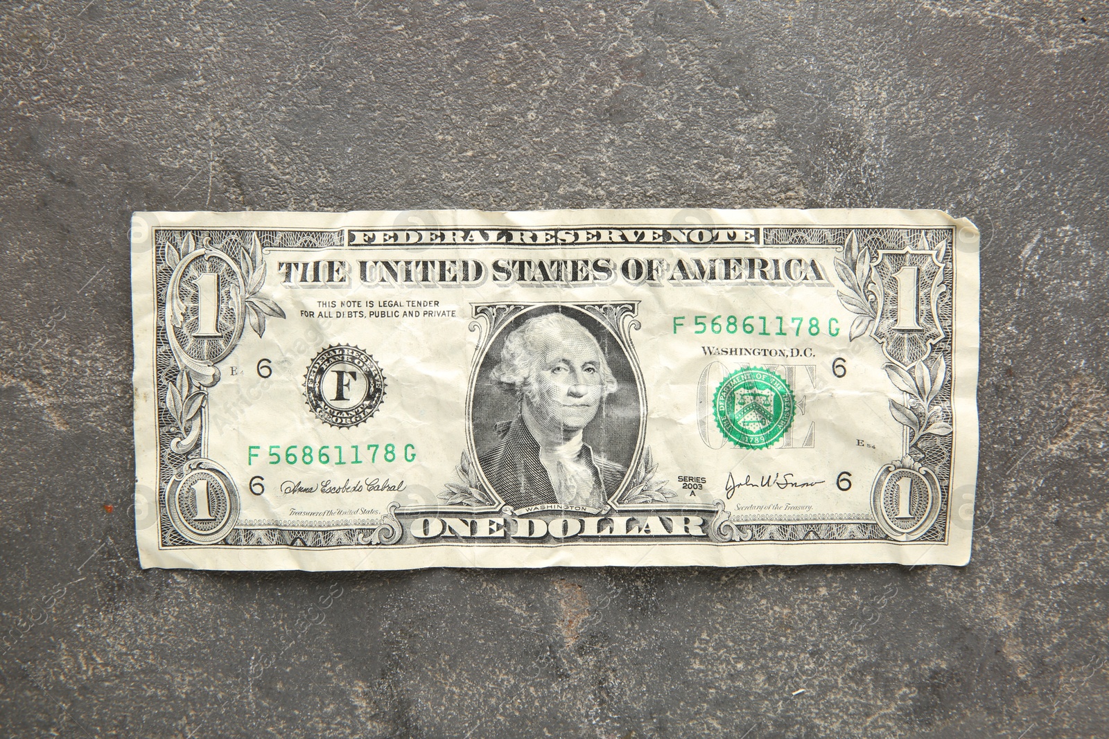 Photo of One crumpled dollar banknote on grey table, top view