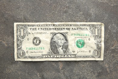 Photo of One crumpled dollar banknote on grey table, top view