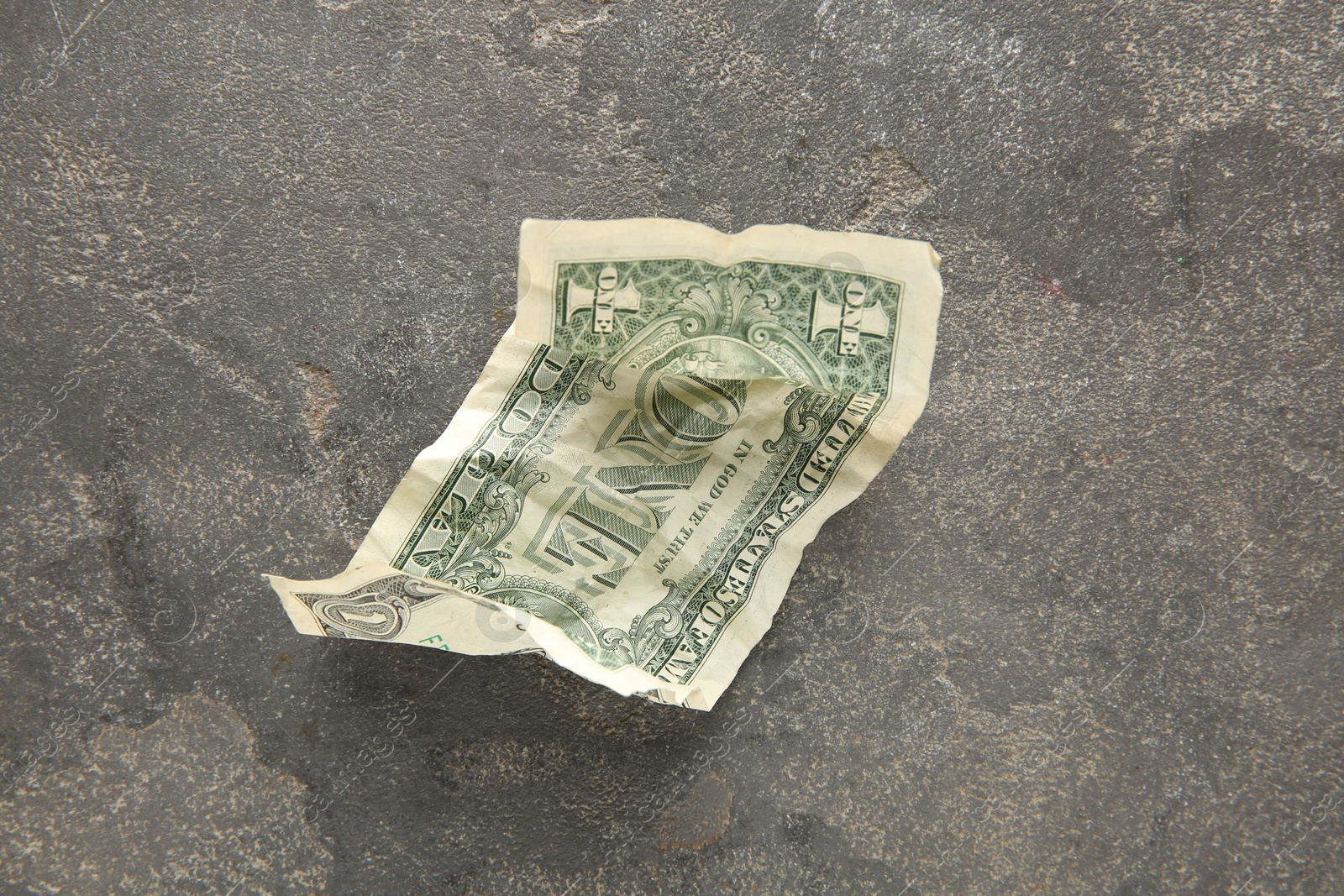 Photo of One crumpled dollar banknote on grey table, top view