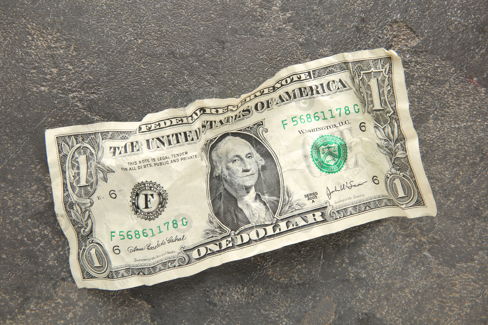 Photo of One crumpled dollar banknote on grey table, top view