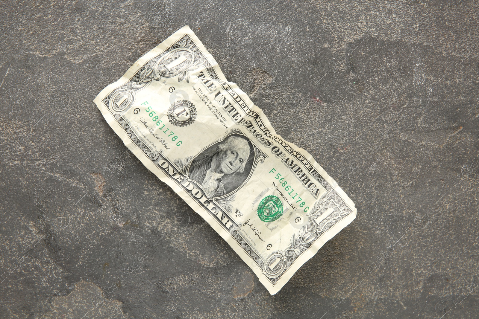 Photo of One crumpled dollar banknote on grey table, top view