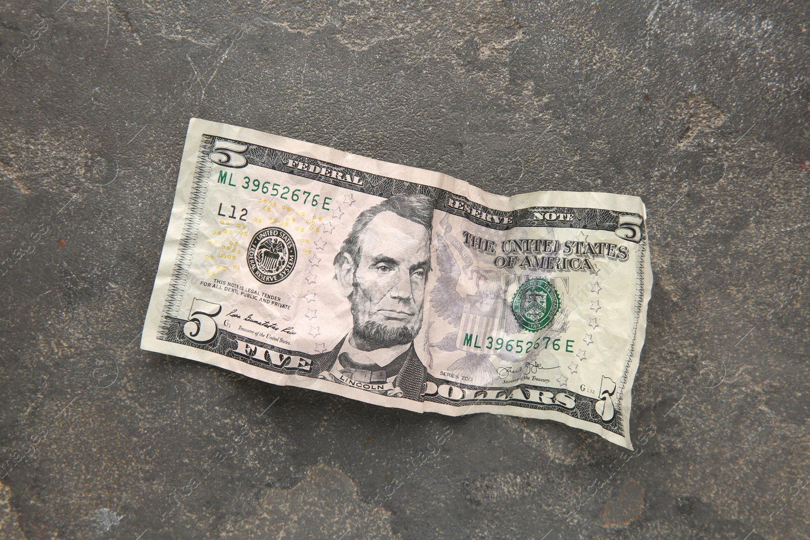 Photo of One crumpled dollar banknote on grey table, top view