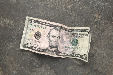 Photo of One crumpled dollar banknote on grey table, top view