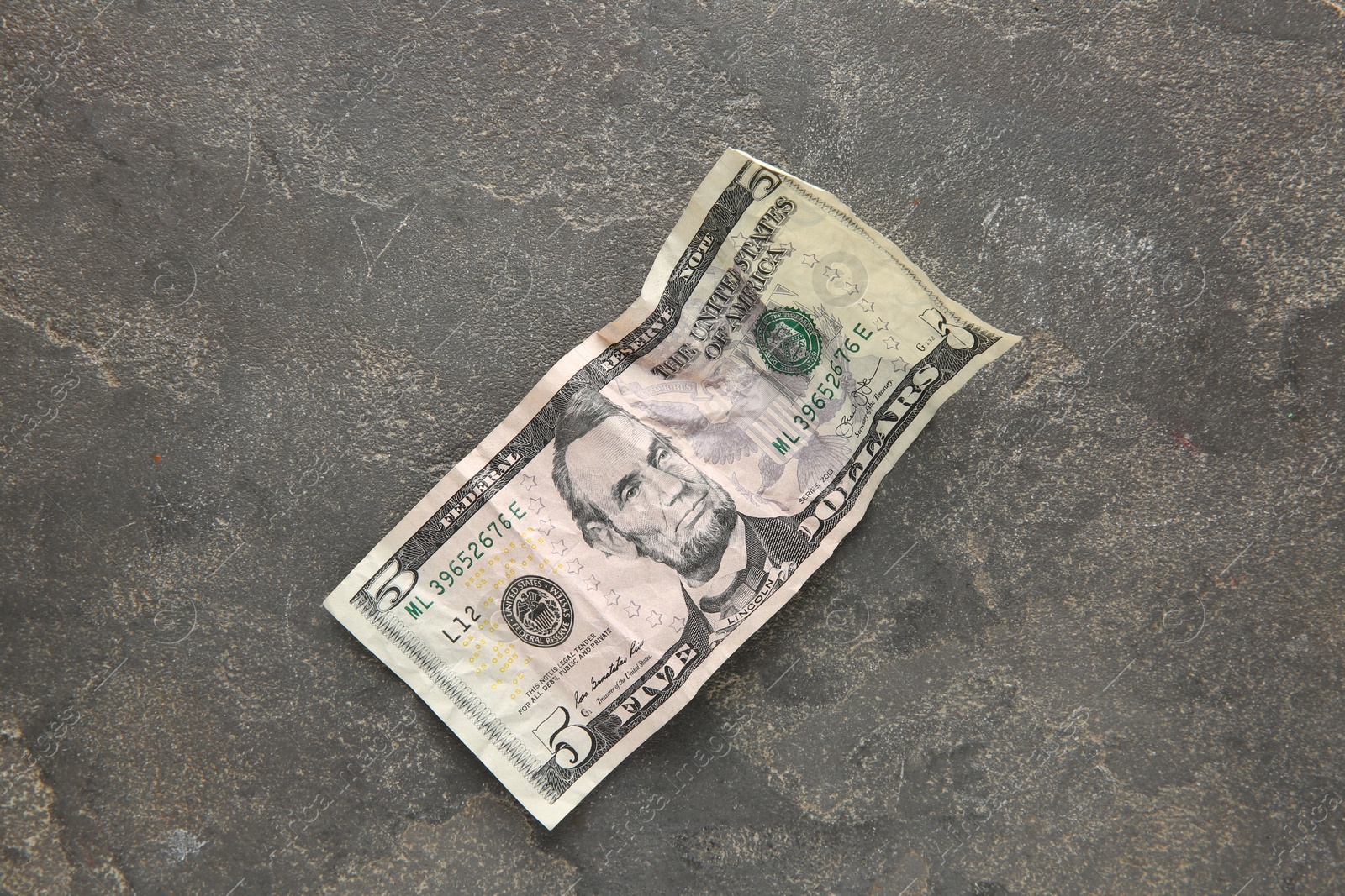 Photo of One crumpled dollar banknote on grey table, top view