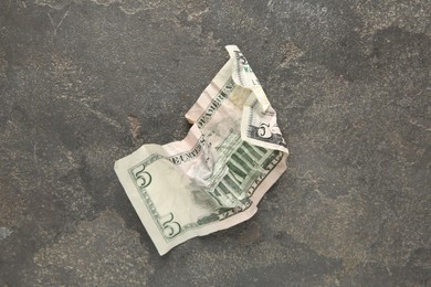 Photo of One crumpled dollar banknote on grey table, top view