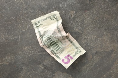 Photo of One crumpled dollar banknote on grey table, top view